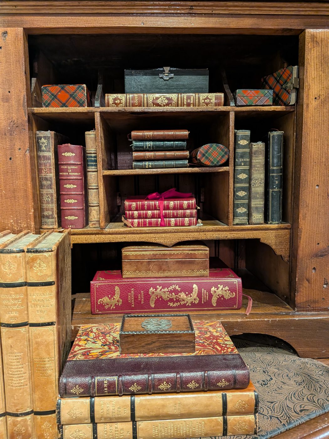 Antique leather-bound books and gilt-tooled volumes in a fitted desk cabinet