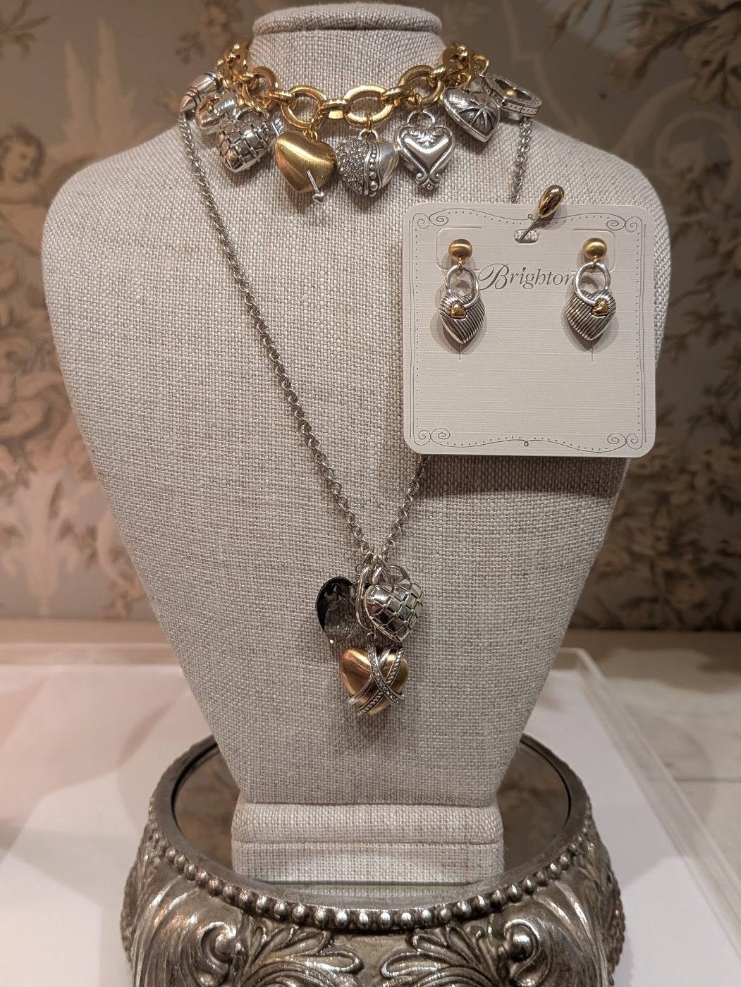 Brighton charm bracelet, heart necklace and earrings on a linen display