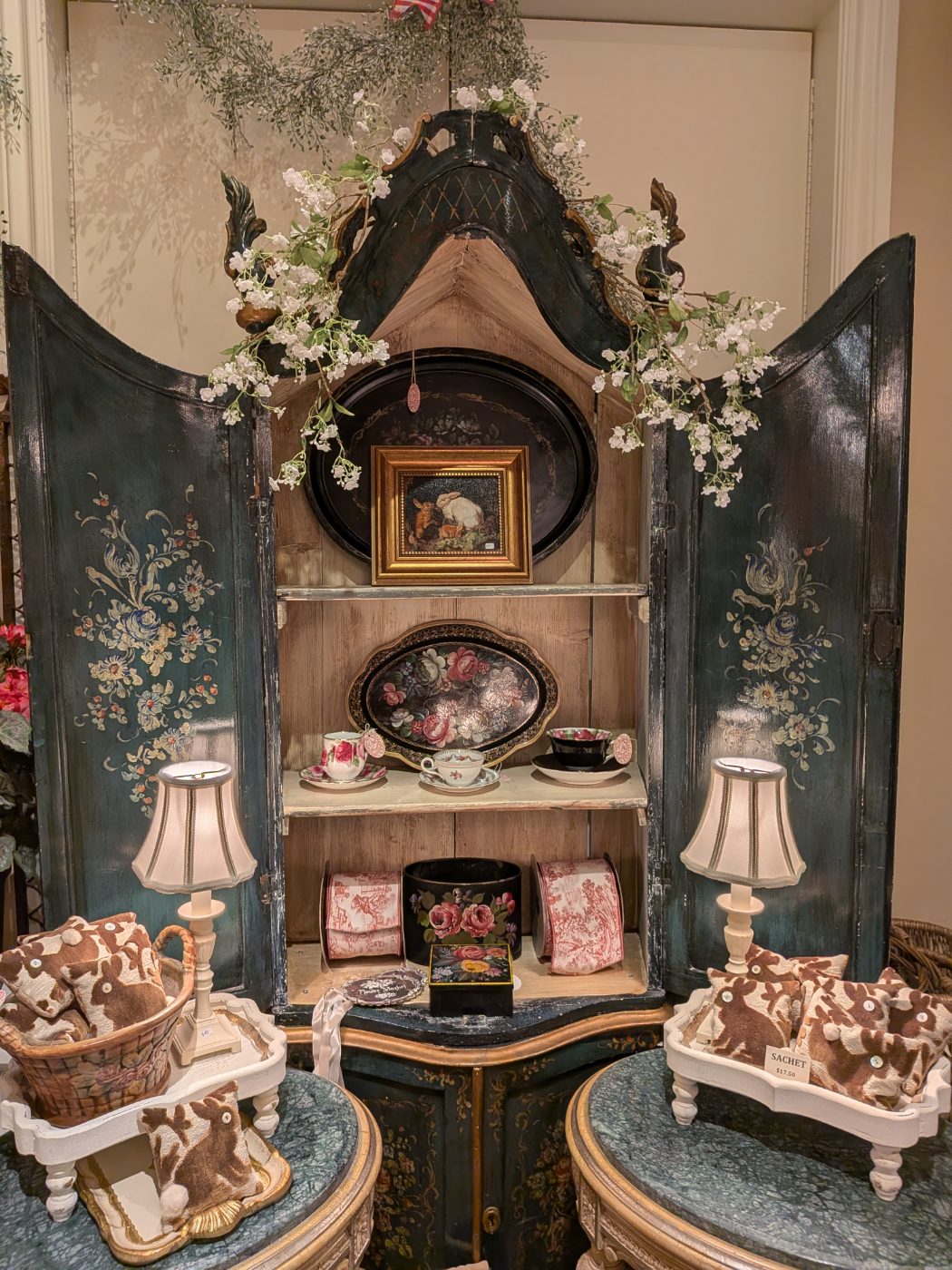 Antique teal painted cabinet styled with florals, tole trays and toile sachets
