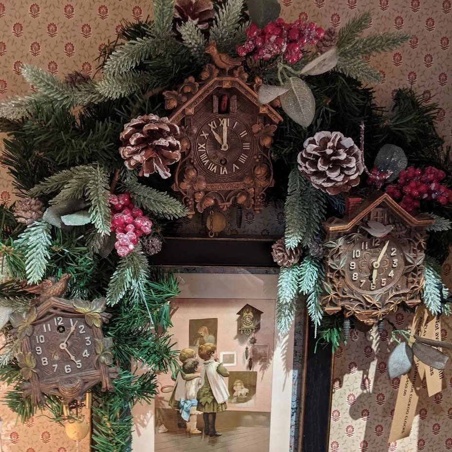 Antique cuckoo clocks framed by frosted pine, pinecones and red berries