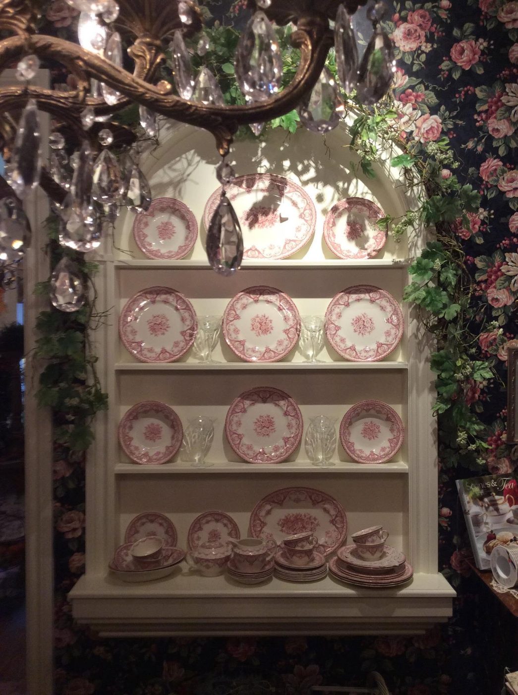 Red transferware china displayed in an arched hutch